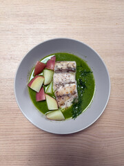 A plate of barramundi with green herb sauce.