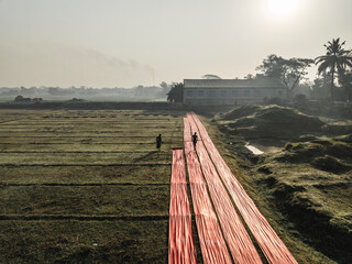 Aerial view of a cloth factory with people drying fabric in a rural landscape, Paikar Char, Narsingdi, Dhaka, Bangladesh.