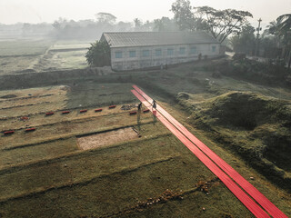 Aerial view of a cloth factory with people drying cloth in a rural landscape, Paikar Char, Narsingdi, Dhaka, Bangladesh.