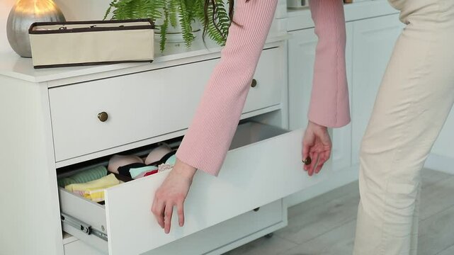 Woman putting organizer with different socks into drawer at home, closeup
