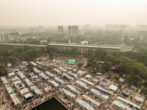 Aerial view of a vibrant book fair with bustling stalls and high-rise buildings, Shahbag, Dhaka, Bangladesh.