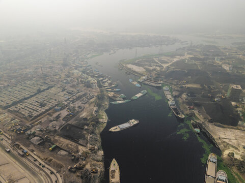 Aerial view of Buriganga river with boats and urban cityscape, Amin Bazar, Savar, Dhaka, Bangladesh.