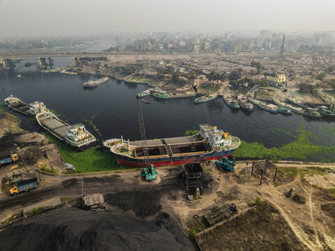 Aerial view of an industrial coal factory with ships and boats along the river, Amin Bazar, Savar, Dhaka, Bangladesh.