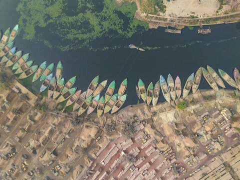 Aerial view of busy boats on the Buriganga river with cement industries and vibrant residential area, Darus Salam Thana, Dhaka, Bangladesh.