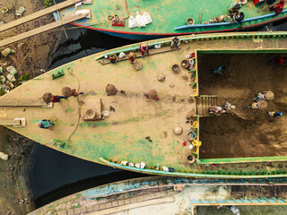 Dhaka, Bangladesh - 02 February 2025: Aerial view of people working with boats and cement industries along the Buriganga River, Darus Salam Thana, Dhaka, Bangladesh.