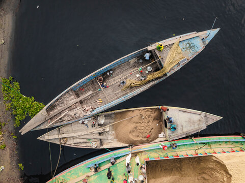 Aerial view of busy boats and people working along the Buriganga river with cement industries, Darus Salam Thana, Dhaka, Bangladesh.