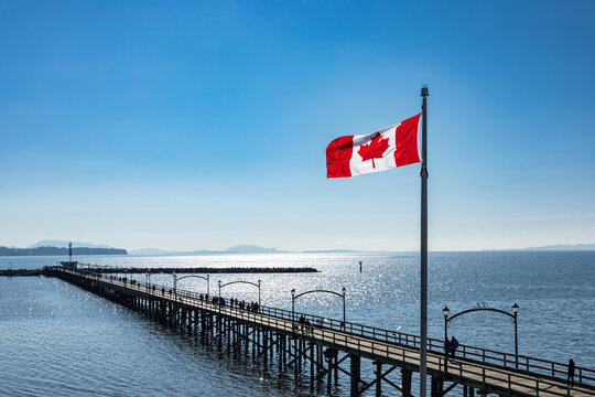 Fototapeta White Rock city pier in the dusk with flying Flag of Canada, British Columbia, Canada.
