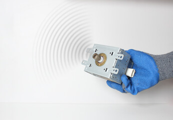 Spare parts of the microwave in the hand in a blue glove