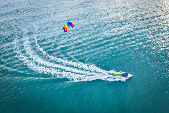 Aerial view of colorful parasailing and speedboats on the blue ocean with a clear sky, Kampung Lubok Buaya, Langkawi, Malaysia.