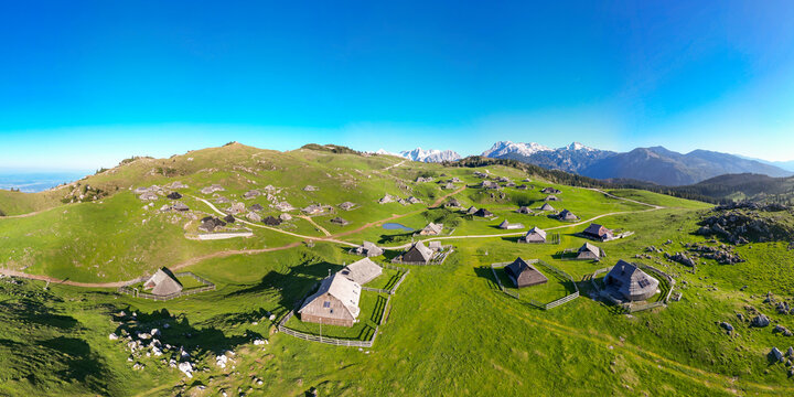 Aerial view of beautiful alpine pasture with chalets and cabins amidst green meadows and mountains, Velika Planina, Kamnik, Slovenia.