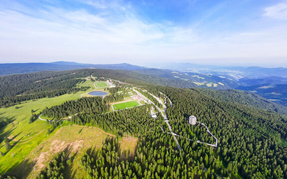 Aerial view of serene forest and picturesque mountain resort with lush greenery and clear sky, Pohorje, Stajerska, Slovenia.