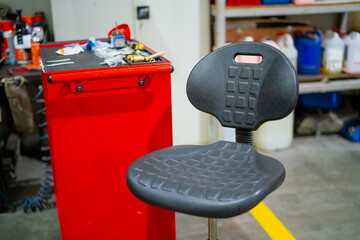 Darker grey creeper chair. Industrial mechanic workshop chair. Rotating mechanics chair in garage...