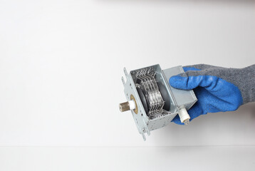 Spare parts of the microwave in the hand in a blue glove