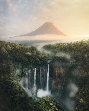 Aerial view of Tumpak Sewu waterfall surrounded by lush forest and majestic mountains, Pronojiwo, Lumajang, East Java, Indonesia.
