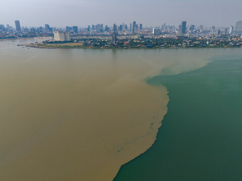Aerial view of the merging rivers of Mekong and Tonle Sap with a vibrant city skyline, Akreiy Ksatr, Kandal, Cambodia.