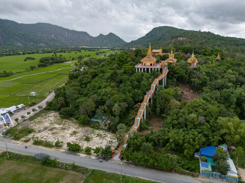 Aerial view of a serene pagoda and temple amidst lush greenery and hills, Tri Ton, An Giang, Vietnam.
