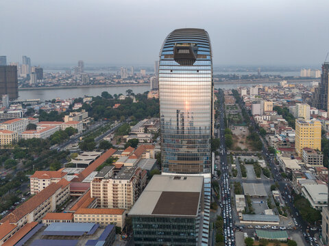 Aerial view of the modern Vattanac Tower reflecting in the river amidst a bustling cityscape, Daun Penh District, Phnom Penh, Cambodia.