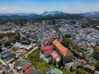 Aerial view of vibrant cityscape with residential buildings and lush greenery surrounded by mountains, Ward 9, Da Lat, Lam Dong, Vietnam.
