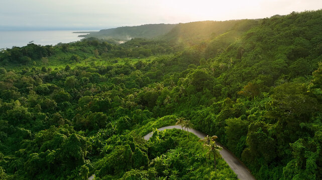 Aerial view of a curvy road winding through lush tropical forest at sunset, Port Vila, Efate, Vanuatu.