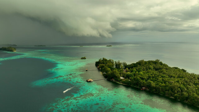 Aerial view of a tropical island with lush greenery and turquoise water under overcast skies, Western Province, Solomon Islands.