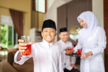 Portrait of the Indonesian Muslim boy holding a drink while celebrating Eid Mubarak. Concept of Happy Lebaran, Eid Al Fitr, Idul Fitri, and Ramadan Mubarak celebration
