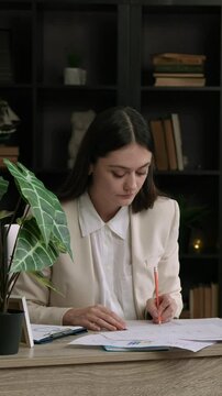 Woman works at an office table at the computer and makes notes in documents. Business woman works on an important and complex project and yawns from fatigue. Dedication and continuous work