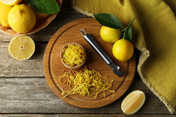 Lemon zest, zester tool and fresh fruits on wooden table, flat lay