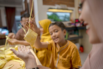 Indonesian Muslim family weaving ketupat rice dumpling from young coconut leaves. Traditional Muslim food during celebration of Happy Lebaran, Eid Al Fitr, Idul Fitri, and Ramadan Mubarak celebration