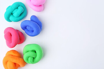 Naklejka premium Different colorful play dough on white background, flat lay. Space for text