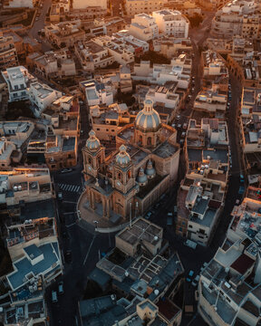 Aerial view of st. mary's parish church surrounded by historic buildings and scenic streets at sunset, dingli, malta.