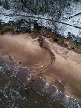 Aerial view of the tranquil and scenic coastline with cliffs and a snowy beach, Salacgriva Parish, Limbazi, Latvia.