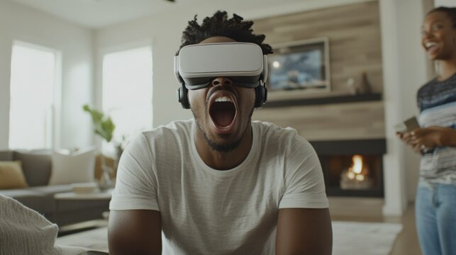 Excited African American man enjoying virtual reality experience at home, showcasing joy and engagement while wearing VR headset with a cozy interior backdrop