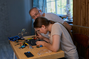Grandfather and granddaughter work together on an electronics project