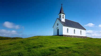Fototapeta premium Pristine white chapel sits on a verdant hillside under a deep blue sky, its tall spire and simple stone design offering a tranquil, minimalist sanctuary in a rural landscape.