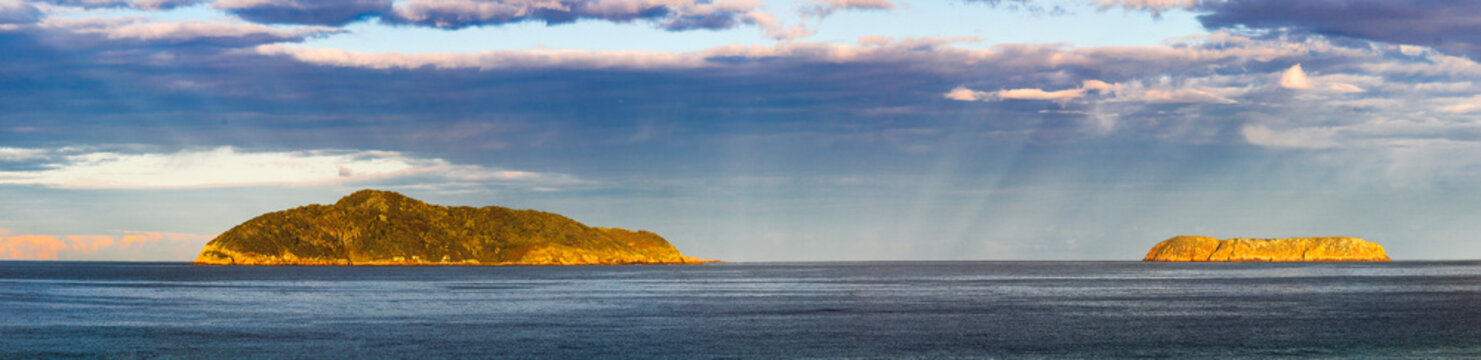 Rays of light coming up from the horizon between islands on the horizon