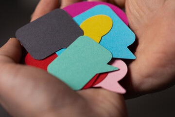 Hand holding multiple colorful speech bubbles.  Concept of communication, ideas, feedback.