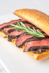 Grilled ciabatta sandwich with melted cheese, juicy steak, caramelized onions, and rosemary