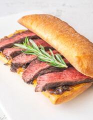 Grilled ciabatta sandwich with melted cheese, juicy steak, caramelized onions, and rosemary