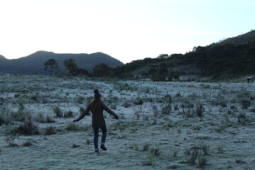 mulher camimhando em grama coberta por geada no amanhecer em urubici, santa catarina