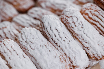 Freshly baked eclairs coated with powdered sugar in a bakery factory