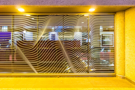 Abstract metal designs in a window lit by artificial lighting.