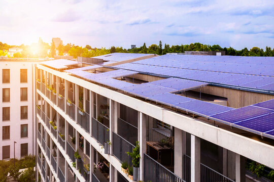 Solar Panels Roof of Modern Residential Apartment Building Block of Flats in Green City with Sun Light.