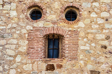Pareidolia. Two circular windows and an elongated window, which looks like a face in a stone wall in the town of Pedraza, province of Segovia. Spain