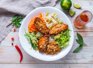Garlic Chicken Wings with rice vermicelli noodles, fresh vegetables, and crushed peanuts served in plate isolated on wooden background top view of Hong Kong food