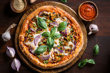 Delicious gourmet pizza with fresh vegetables and basil on a wooden board