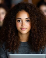 Young woman studies intently at university computer lab surrounded by focused classmates engaged in their own projects