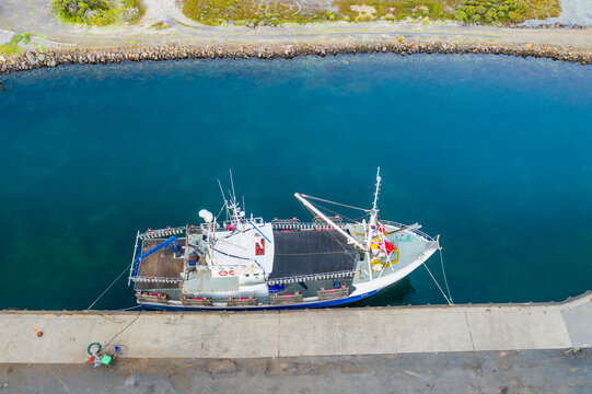 Looking down a solitary fishing boat docked in a coastal channel