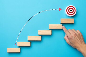 Conceptual image of stepping blocks and hand pointing to target goal, symbolizing progress, growth, and achieving success
