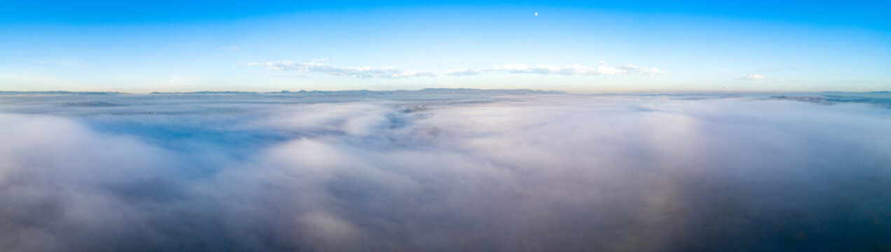 Sea of fog over countryside with moon in the sky at dawn