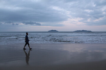 Naklejka premium homem caminhando em praia no nascer do sol em florianópolis, santa catarina